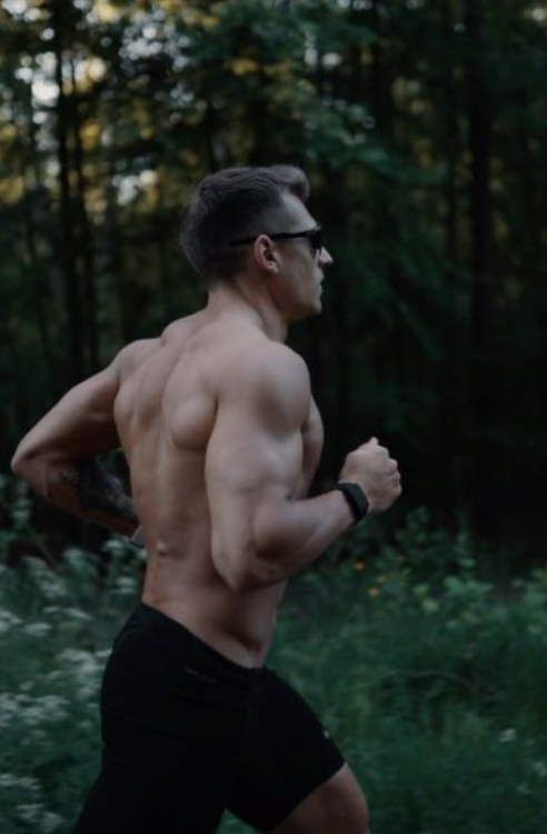 Man running shirtless in a forest
